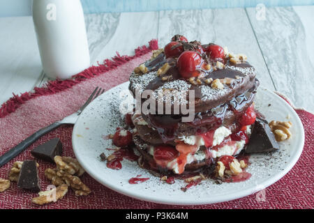 Leckere Schokolade Pfannkuchen - Gourmet Dessert zum Frühstück? Nahaufnahme des gestapelte Pfannkuchen garniert mit Kirschen, Sahne und Walnüssen. Verschiedene Winkel Stockfoto