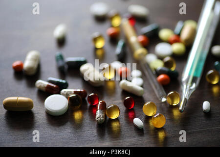 Farblich unterschiedliche Medikationen und Tabletten auf einer hölzernen Textur Tabelle Stockfoto