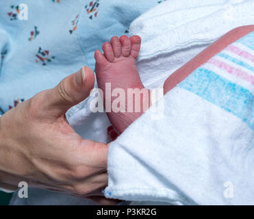 Mutter sanft Holding Fuß des neugeborenen Sohn Stockfoto