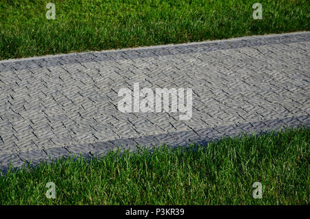 Ein schöner neuer Gehweg aus Stein befindet sich in den grünen Gras entfernt Stockfoto