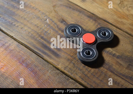 Eine seltene handgefertigten Holzmöbeln zappeln Spinner liegt auf einem braunen Holz- hintergrund Oberfläche. Trendy Anti-Stress-Spielzeug entlasten Stockfoto