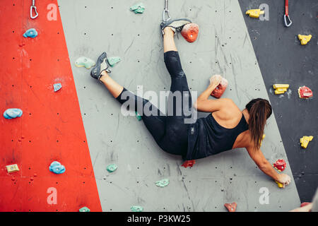 Schöne junge Frau einen großen Schritt bis eine künstliche Wand Stockfoto