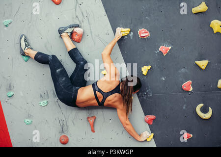 Schöne junge Frau einen großen Schritt bis eine künstliche Wand Stockfoto