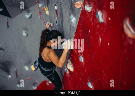 Schöne junge starke Frau klettern auf rote künstliche Wand Ansicht von oben. Stockfoto