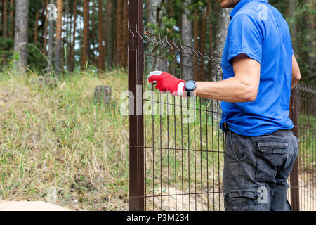 Arbeitnehmer Installation von geschweisstem Metall Gitterzaun Stockfoto