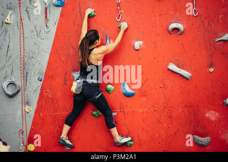 Schöne junge Frau einen großen Schritt bis eine künstliche Wand Stockfoto