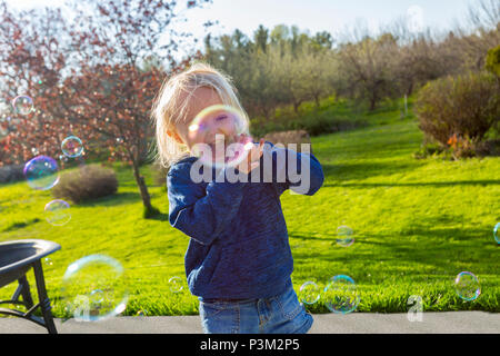 Kaukasische Kleinkind spielen mit Seifenblasen im Freien Stockfoto