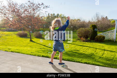 Kaukasische Kleinkind spielen mit Seifenblasen im Freien Stockfoto