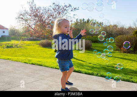 Kaukasische Kleinkind spielen mit Seifenblasen im Freien Stockfoto