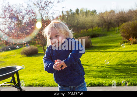 Kaukasische Kleinkind spielen mit Seifenblasen im Freien Stockfoto