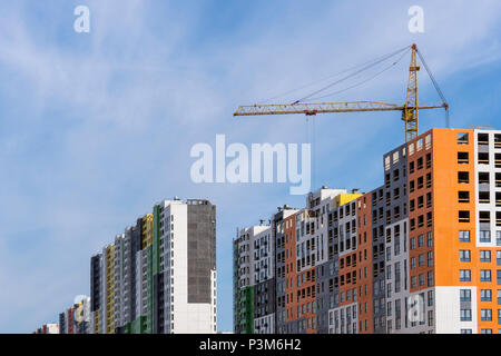 Große gelbe Baukran, mehrstöckiges Haus gegen den blauen Himmel Stockfoto