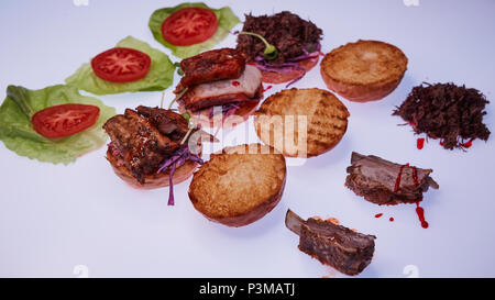 Drei offene Burger mit verschiedenen Füllungen mit einer zerrissenen Schweinefleisch, mit Rippen und Schweinerippchen auf einem weißen Tisch Stockfoto