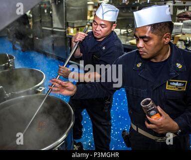 160711-N-SJ 730-052 SOUTH CHINA SEA (11. Juli 2016) Kulinarische Specialist 2. Klasse Yul Marchan, gebürtig aus San Diego, weckt während Chief kulinarische Spezialist Emmanuel Torquido, gebürtig aus San Francisco, Gewürze fügt ein Gericht in der Vorbereitung für das Abendessen an Bord Hospital Ship USNS Mercy (T-AH 19). Barmherzigkeit, die zur Unterstützung der pazifischen Partnerschaft 2016 bereitgestellt wird, ist auf dem Weg zu seinem dritten Mission Halt in Da Nang, Vietnam. Bei der Ankunft, partner Nationen werden Seite an Seite mit lokalen militärischen und nicht-staatlichen Organisationen kooperative Gesundheit Projekte zu leiten, Gemeinschaft Bezug Veranstaltungen und Subje Stockfoto