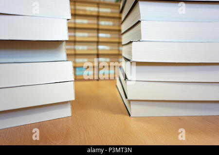 Marke neue weiße Bücher auf dem Schreibtisch in der Bibliothek gestapelt. Bibliothek Katalog im Hintergrund. Akademisches Lernen und Wissen Konzept Stockfoto