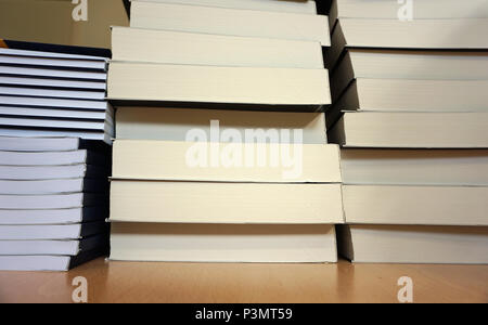 Neue Bücher mit weißen Seiten auf dem hölzernen Tisch stapeln. Bildung, Wissen und Wissenschaft Hintergrund Konzept Stockfoto
