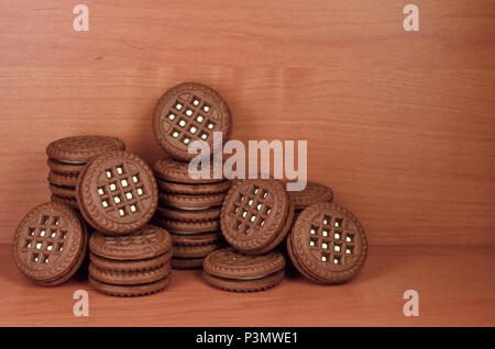 Haufen Chocolate Chip Cookies mit Weiße Vanille Creme gefüllt liegt auf Holz- braune Oberfläche. Süßes und leckeres Sandwich runde Kekse. Detaillierte essen Ph Stockfoto