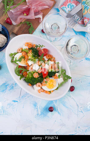 Urlaub Abendessen. Salat mit Gemüse, Shrimps, Ei. Zwei Gläser Wein. Tabelle für das Aufleuchten. Stockfoto