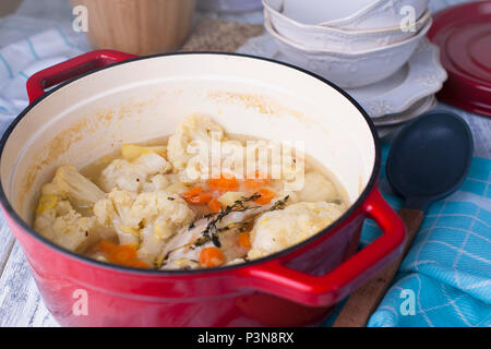 Blumenkohl in einem roten Gusseisen gekocht. Ein blaues Handtuch. Freier Platz für Text. Abendessen mit der Familie. Gemüse. Fertige Gericht. Stockfoto