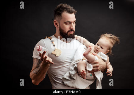 Vater halten und die Pflege von kleinen Säugling Baby, das Füttern aus der Flasche. Stockfoto