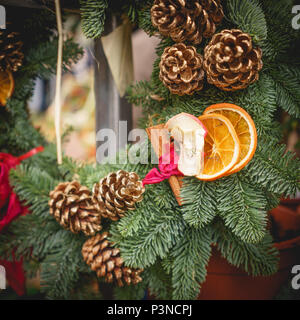 Nahaufnahme einer Christmas wreath Dekoration mit Tannenzapfen, Orangenscheiben und roten Bändern. Urlaub Konzept. Quadratischen Format. Stockfoto