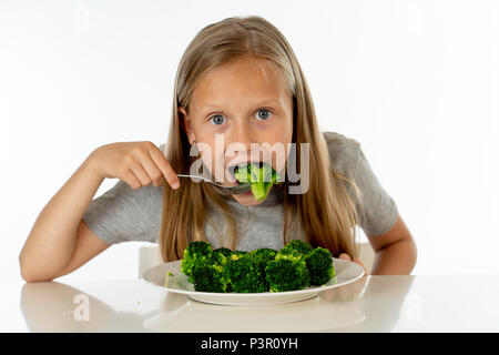 Glückliche junge blonde Mädchen mit Daumen nach oben genießen und Lieben ihres Brokkoli Gemüse essen auf einem Teller mit Messer und Gabel in der gesunden Kinder essen Co Stockfoto