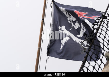 Pirate Fahne im Wind flattern auf einem Mast auf einem Piratenschiff Replik, Hafen von Penzance, Cornwall, England, Großbritannien Stockfoto