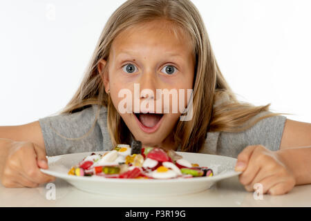 Recht glücklich Zucker hoch kaukasischen weibliches Kind essen Teller voller Süßigkeiten mit Messer und Gabel in süßen Zucker Missbrauch gefährlich Ernährung und ungesunde Nutr Stockfoto