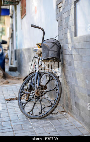 Peking, China - MÄRZ 10, 2016: Fahrräder, Roller und Autos in Peking Straßen. Ein altes Fahrrad wird an der Wand des Hauses platziert. Stockfoto