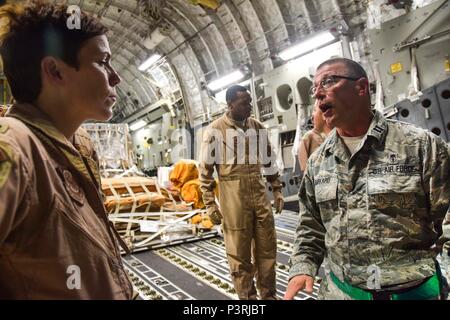 Kapitän Mark Burkard, 379 Expeditionary Medical Group Enroute Patienten Staging Facility eingetragene Krankenschwester, Gespräche mit einem Mitglied der aeromedical evacuation Team über die Patienten auf eine C-17 Globemaster III Juli 18, 2016 belastet, bei Al Udeid Air Base, Katar. Die Patienten wurden auf dem Weg nach Landstuhl Regional Medical Center, Deutschland, ein höheres Maß an Pflege zu erhalten. (U.S. Air Force Foto/Technische Sgt. Carlos J. Treviño) Stockfoto