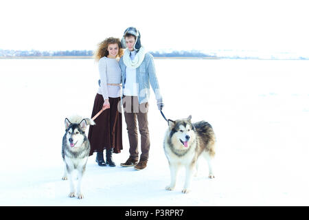 Frau und Mann Wandern mit Huskies in weiss Winter Hintergrund. Stockfoto