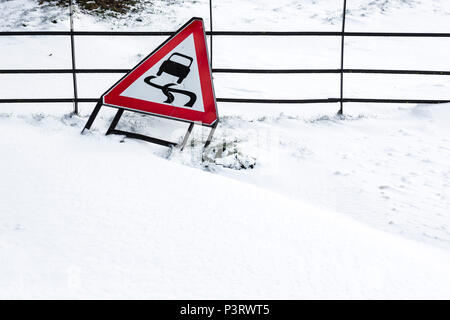 Ein metallzaun teilweise unter Dämme der Schneeverfrachtung mit einem Schild lehnte sich auf es auf glatten Straßen für Vehcile Reisen begraben. Stockfoto