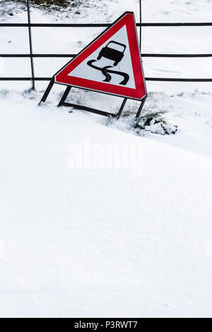 Ein metallzaun teilweise unter Dämme der Schneeverfrachtung mit einem Schild lehnte sich auf es auf glatten Straßen für Vehcile Reisen begraben. Stockfoto