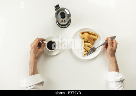 Blick von oben auf die minimalistische Tabelle mit Business Lunch mit Kaffee, Müsli und applie pie. Männliche Hände halten Tasse schwarzen Kaffee und Gabel in breakfas Stockfoto