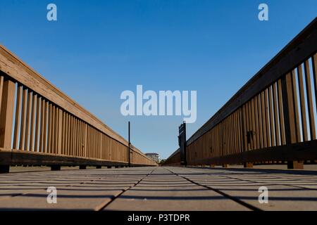 Holzsteg aus niedrigen Perspektive führt zu Vanishing Point unter sonnigen blauen Himmel. Stockfoto