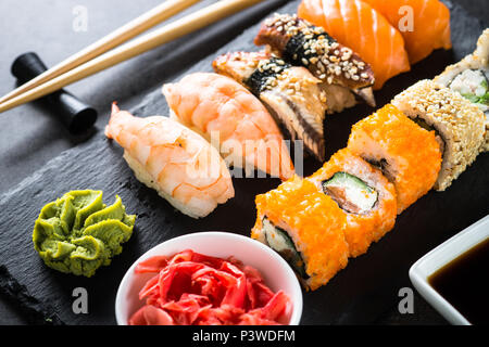 Sushi und Sushi Roll on Black Stone Tabelle einrichten. Traditionelle asiatische Lebensmittel. Stockfoto