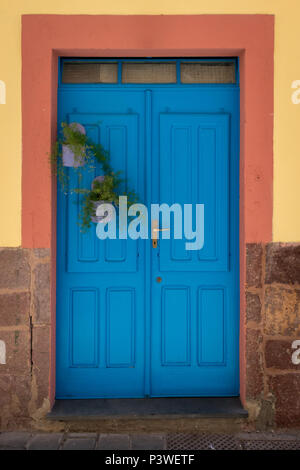 Holz- blaue Tür an einem Haus mit einem gelben Fassade mit rotem Rahmen Stockfoto