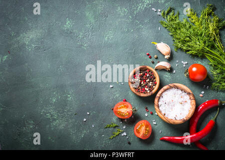 Essen Hintergrund mit Gewürzen, Kräutern und Tomaten auf Tisch aus Stein. Zutaten zum Kochen. Ansicht von oben mit der Kopie. Stockfoto