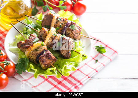 Gegrillte Shish Kebab oder schaschlik auf Spieße mit Salat Blätter auf weiße Platte auf hölzernen Tisch. Stockfoto