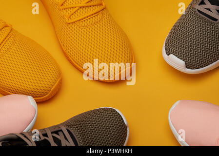 Bunte Sport Schuhe bleiben Sie auf gelben Hintergrund Nähe zu sehen. Stockfoto