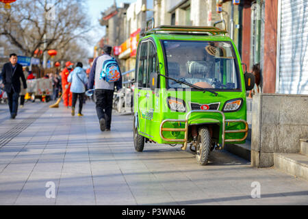 Peking, China - MÄRZ 10, 2016: Leute die Straße entlang. Auf der Straße ist ein geparkten Roller mit einer Kabine. Stockfoto