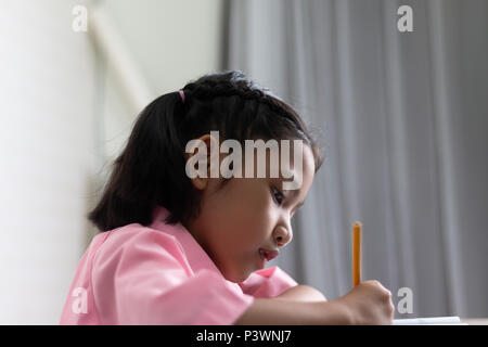 Schließen Sie das kleine Mädchen Hausaufgaben konzentriert zu. Kinder mit einem gelben Bleistift schreibt ein Notebook. Wählen Sie Fokus flache Tiefenschärfe mit kopieren Stockfoto