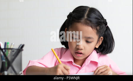 Schließen Sie das kleine Mädchen Hausaufgaben konzentriert zu. Kinder mit einem gelben Bleistift schreibt ein Notebook. Wählen Sie Fokus flache Tiefenschärfe mit kopieren Stockfoto