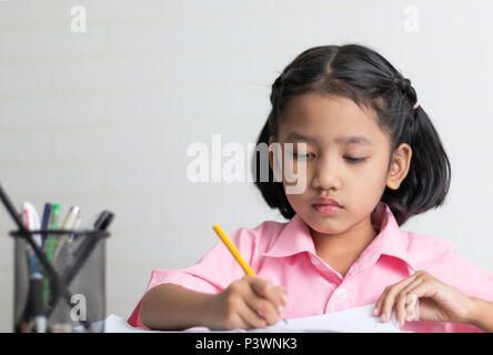 Schließen Sie das kleine Mädchen Hausaufgaben konzentriert zu. Kinder mit einem gelben Bleistift schreibt ein Notebook. Wählen Sie Fokus flache Tiefenschärfe mit kopieren Stockfoto