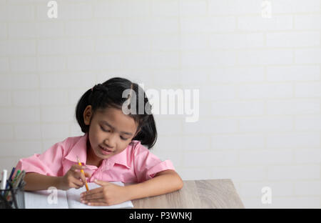 Das kleine Mädchen Hausaufgaben machen glücklich. Kinder mit einem gelben Bleistift. Wählen Sie Fokus flache Tiefenschärfe mit kopieren. Stockfoto