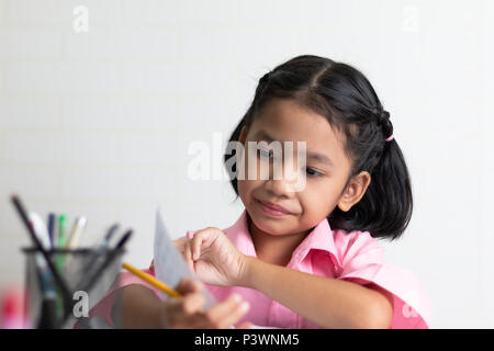 Das kleine Mädchen Hausaufgaben konzentriert zu. Kinder mit einem gelben Bleistift. Wählen Sie Fokus flache Tiefenschärfe. Stockfoto