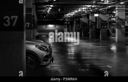 Parkplätze im Einkaufszentrum Einschalten der Leuchten für die Beleuchtung. Silver Auto bei Block 37 über Nacht geparkt. Überdachter Parkplatz. Stockfoto