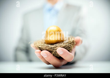 Altersvorsorge Golden Nest Ei in einer businessmans Hand Stockfoto