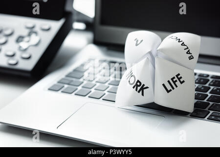 Origami Fortune Teller auf Laptop im Büro Konzept für Work Life Balance Entscheidungen Stockfoto