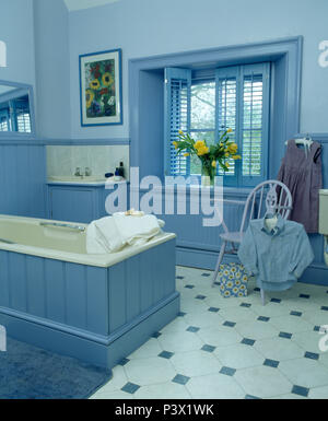 Blaue Fensterläden auf Fenster in blau Badezimmer mit tonque + Nut getäfelten Badewanne und checkrboard Fliesenboden Stockfoto