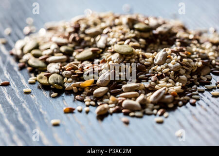 Trockenen Samen Kürbis, Sesam, Sonnenblumen, Flachs für gesunde Ernährung auf dem hölzernen schwarz Tabelle gemischt. Stockfoto